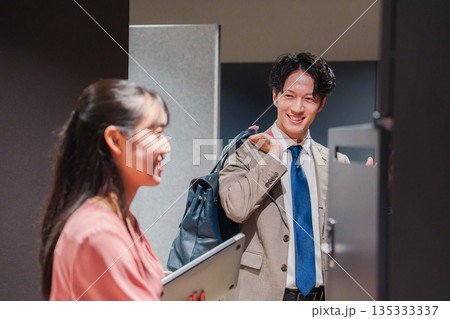 オフィスのロッカーで会話をする男女の会社員 オフィスのロッカーで会話をする男女の会社員 135333337