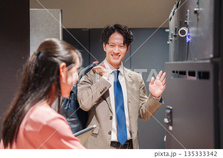 オフィスのロッカーで会話をする男女の会社員 オフィスのロッカーで会話をする男女の会社員 135333342