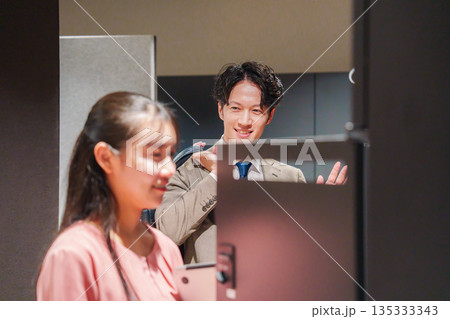 オフィスのロッカーで会話をする男女の会社員 135333343