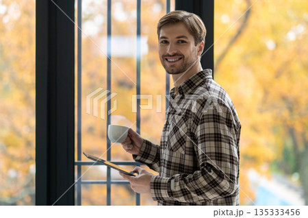 Young man in plaid shirt looking confident and smiling nicely Young man in plaid shirt looking confident and smiling nicely 135333456