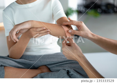 Nurse assisting young girl with skin injury care indoors Nurse assisting young girl with skin injury care indoors 135333529