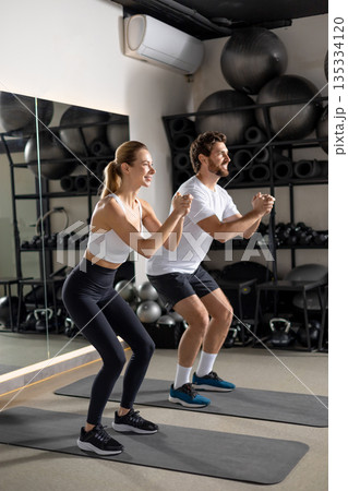 Two young people exercising in the gym in squatting position Two young people exercising in the gym in squatting position 135334120