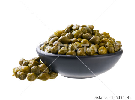 pickled capers in a black ceramic bowl isolated on a white background. 135334146