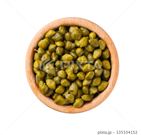 pickled capers in a wooden bowl isolated on a white background, top view. 135334152
