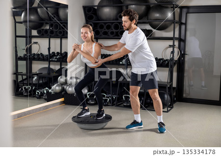 Blonde young woman exercising in the gym with a coach 135334178