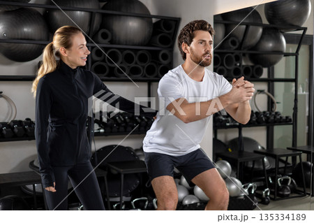 Blonde young female coach training a young man during interval workout Blonde young female coach training a young man during interval workout 135334189