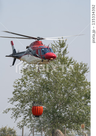 Helicopter Carrying Water Bucket for Firefighting Action 135334392