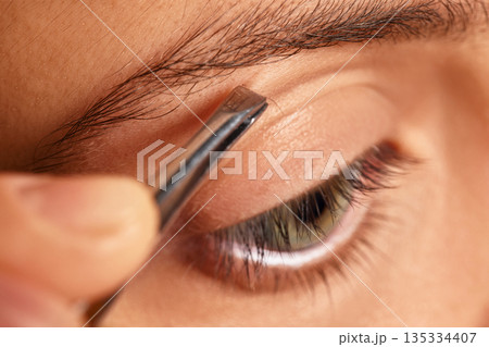Woman tweezing her eyebrow, shaping and maintaining facial appearance 135334407