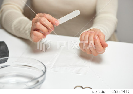 Woman filing fingernails during personal self-care beauty routine 135334417