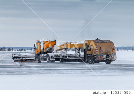Snowplow cleans airport taxiway in a snowstorm 135334599