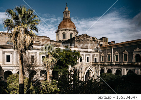 Benedictine Monastery Of San Nicolo Arena In Catania, Sicily: Historic Baroque Courtyard With Arched Walkways, Stone Facades, And Domed Church Structure Benedictine Monastery Of San Nicolo Arena In Catania, Sicily: Historic Baroque Courtyard With Arched Walkways, Stone Facades, And Domed Church Structure 135334647