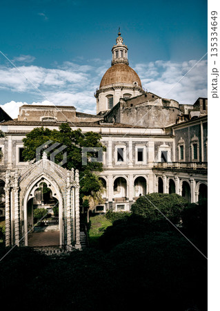 Benedictine Monastery Of San Nicolo Arena In Catania, Sicily: Historic Baroque Courtyard With Arched Walkways, Stone Facades, And Domed Church Structure Benedictine Monastery Of San Nicolo Arena In Catania, Sicily: Historic Baroque Courtyard With Arched Walkways, Stone Facades, And Domed Church Structure 135334649