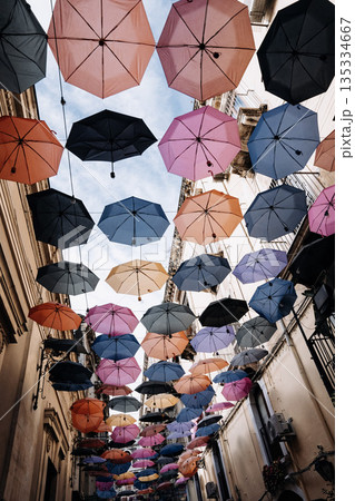 Colorful Umbrellas Hanging Above Narrow Street In Catania: Decorative Canopy Creating Vibrant Urban Scene With Light And Shadow Colorful Umbrellas Hanging Above Narrow Street In Catania: Decorative Canopy Creating Vibrant Urban Scene With Light And Shadow 135334667