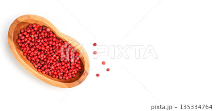 Red or Pink peppercorn in small wooden bowl, some scattered on board near, closeup photo from above isolated with white background Red or Pink peppercorn in small wooden bowl, some scattered on board near, closeup photo from above isolated with white background 135334764