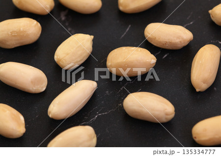 Group of peeled peanuts on black marble like board, closeup detail from above 135334777