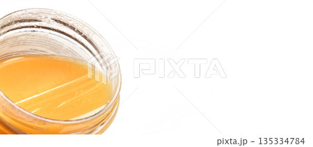 Glass jar with amber coloured honey, closeup detail, isolated on white background, space for text right side Glass jar with amber coloured honey, closeup detail, isolated on white background, space for text right side 135334784