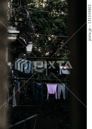 Hanging Laundry In Catania Courtyard With Italian Style: Colorful Clothes Drying On Lines Between Residential Buildings In Quiet Everyday Urban Scene Hanging Laundry In Catania Courtyard With Italian Style: Colorful Clothes Drying On Lines Between Residential Buildings In Quiet Everyday Urban Scene 135334803