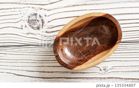 Small polished rosewood bowl on white boards desk, closeup view from above 135334807