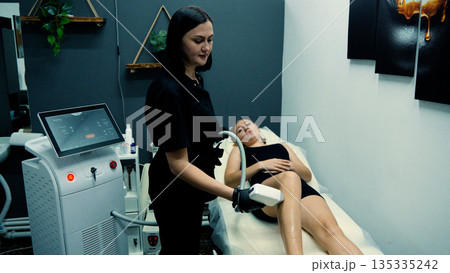 Beautician performing laser treatment on legs Beautician performing laser treatment on legs 135335242