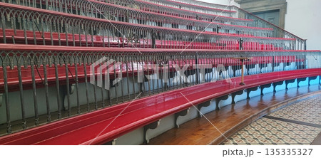 A view of empty, multi-tiered, antique wooden classroom seats with decorative railings in a historic interior. Educational system concept, timeless design. A view of empty, multi-tiered, antique wooden classroom seats with decorative railings in a historic interior. Educational system concept, timeless design. 135335327
