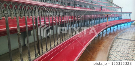 A view of empty, multi-tiered, antique wooden classroom seats with decorative railings in a historic interior. Educational system concept, timeless design. 135335328