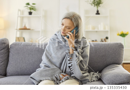 Elderly Woman Suffering From Cold, Talking On Phone At Home Elderly Woman Suffering From Cold, Talking On Phone At Home 135335430