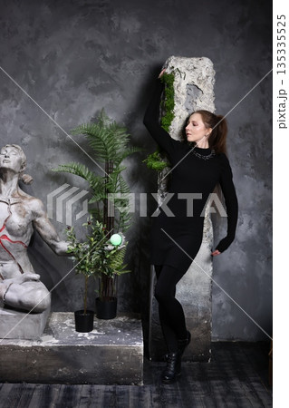 Contemplating woman resting beside artistic stone sculpture and greenery Contemplating woman resting beside artistic stone sculpture and greenery 135335525