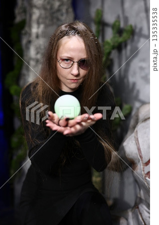 Tranquil woman gently clasping illuminating orb in studio environment 135335538