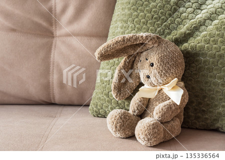 Plush Bunny on Sofa with Green Pillow. Cozy Childhood Inspired Background 135336564
