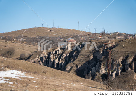 Rocky Armenian landscape with deep gorge, dry hills, scattered houses, patches of melting snow, creating a calm rural mood Rocky Armenian landscape with deep gorge, dry hills, scattered houses, patches of melting snow, creating a calm rural mood 135336782