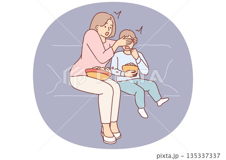Shocked mother closes son eyes while watching television show with scenes of violence 135337337