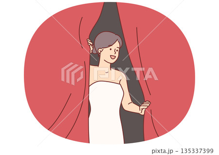 Woman superstar looks out from behind curtains of theater, waiting to go on stage 135337399