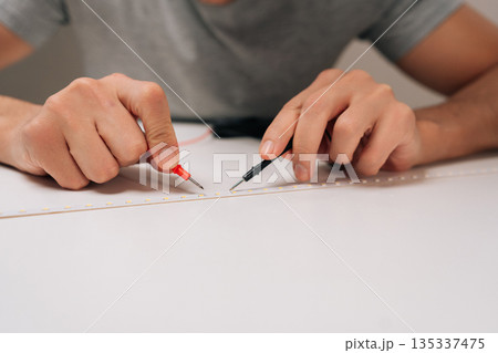 Person testing led strip light circuit with multimeter probes, hands holding the measurement tools while checking electrical properties and repairing electronics with expertise. Person testing led strip light circuit with multimeter probes, hands holding the measurement tools while checking electrical properties and repairing electronics with expertise. 135337475