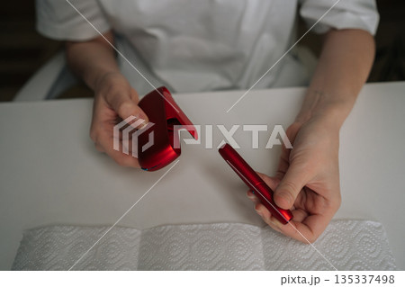Overhead view of person disassembling red electronic cigarette, separating components for thorough cleaning and routine service, demonstrating the necessary maintenance process for vape device. 135337498
