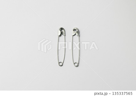 Two silver safety pins isolated on white background Two silver safety pins isolated on white background 135337565