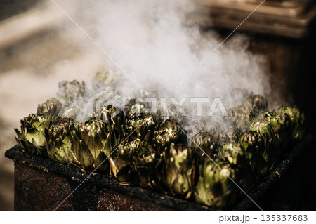 Fresh Artichokes Barbecue At Catania Market In Sicily: Trimming And Steaming Green Vegetables On Hot Surface In Traditional Street Food Scene Fresh Artichokes Barbecue At Catania Market In Sicily: Trimming And Steaming Green Vegetables On Hot Surface In Traditional Street Food Scene 135337683