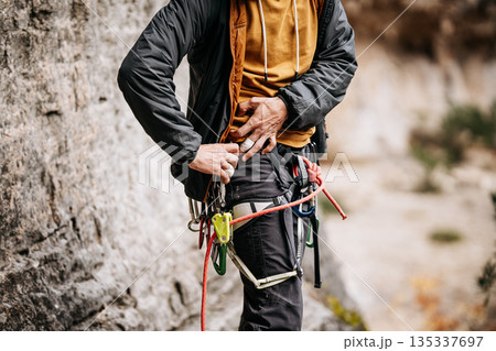 Rock Climber Attaching Ohm Device To Harness: Taped Fingers, Safety Equipment, And Rope System During Preparation At Natural Rock Wall 135337697