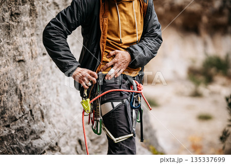 Rock Climber Attaching Ohm Device To Harness: Taped Fingers, Safety Equipment, And Rope System During Preparation At Natural Rock Wall 135337699