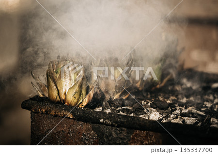 Fresh Artichokes Barbecue At Catania Market In Sicily: Trimming And Steaming Green Vegetables On Hot Surface In Traditional Street Food Scene Fresh Artichokes Barbecue At Catania Market In Sicily: Trimming And Steaming Green Vegetables On Hot Surface In Traditional Street Food Scene 135337700