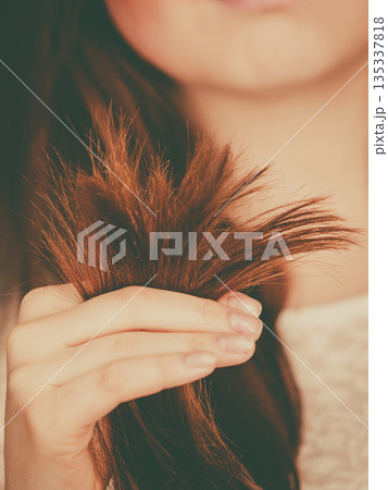 Woman looking at her dry hair ends Woman looking at her dry hair ends 135337818