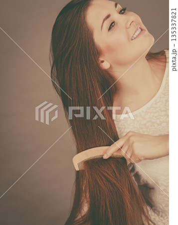 Happy woman brushing her hair Happy woman brushing her hair 135337821