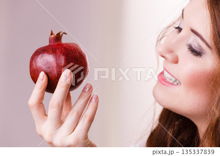 Cheerful woman holds pomegranate fruits 135337839