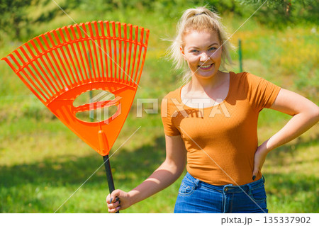 Woman with rake in garden Woman with rake in garden 135337902