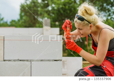 Woman using string as level in wall construction. Woman using string as level in wall construction. 135337906