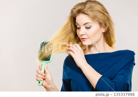 Woman brushing her long hair with brush Woman brushing her long hair with brush 135337998