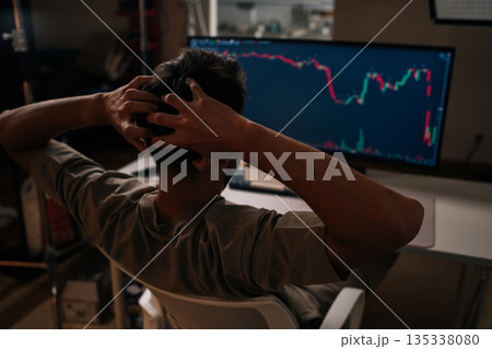 Worried trader in home office stares at red stock and crypto chart on desktop computer, showing sharp bearish downturn and causing stress, anxiety and financial concern. Concept of financial crisis. Worried trader in home office stares at red stock and crypto chart on desktop computer, showing sharp bearish downturn and causing stress, anxiety and financial concern. Concept of financial crisis. 135338080