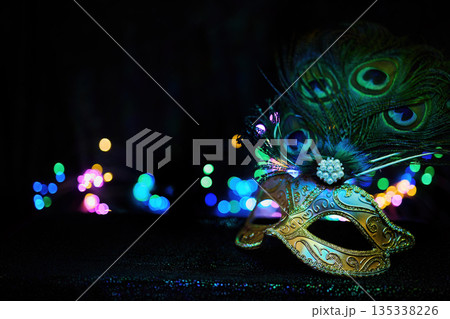 Masquerade mask with peacock feathers, bokeh lights, and mystery 135338226