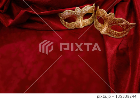 Golden masquerade masks resting on red velvet drapery Golden masquerade masks resting on red velvet drapery 135338244