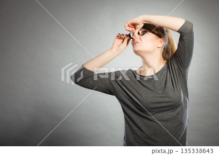 Nerdy girl holding nose. Nerdy girl holding nose. 135338643
