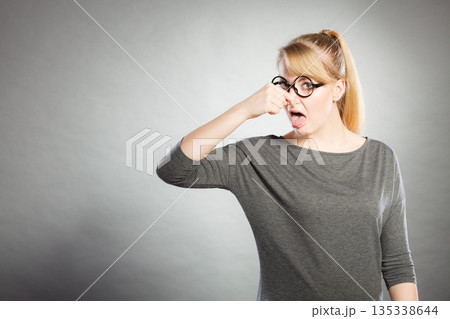 Nerdy girl holding nose. 135338644
